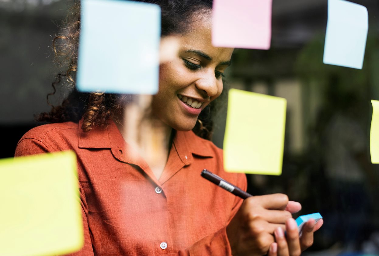 Person using sticky notes to keep track of ideas on a board.