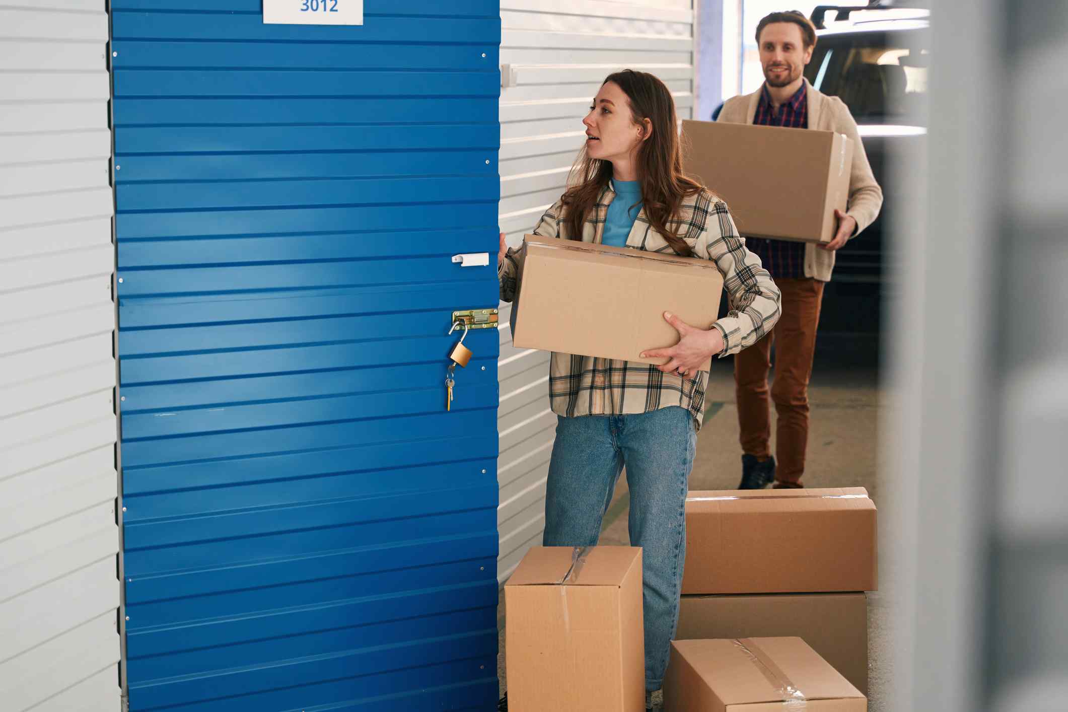 Father helps daughter move boxes into a storage unit.