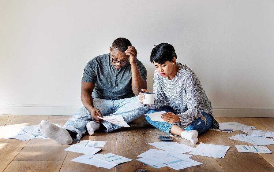 Couple sitting on the ground surrounded by tax papers.