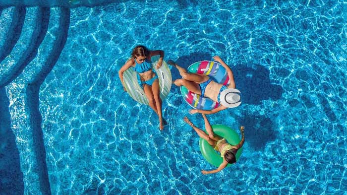 Three girls floating in tubes in a pool on a summer day.