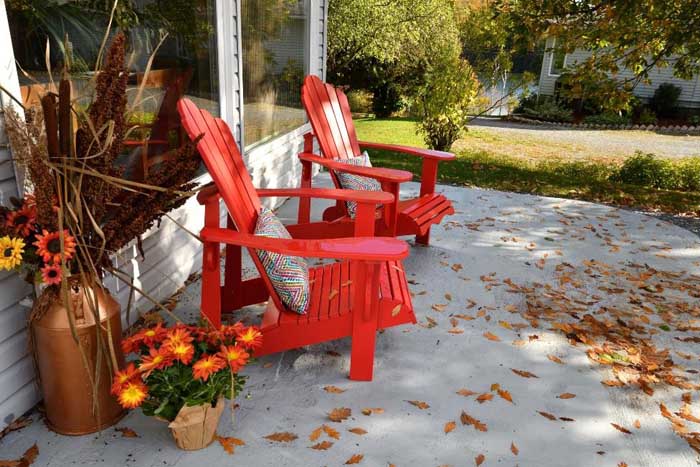 Red patio chairs surrounded by fall leaves.