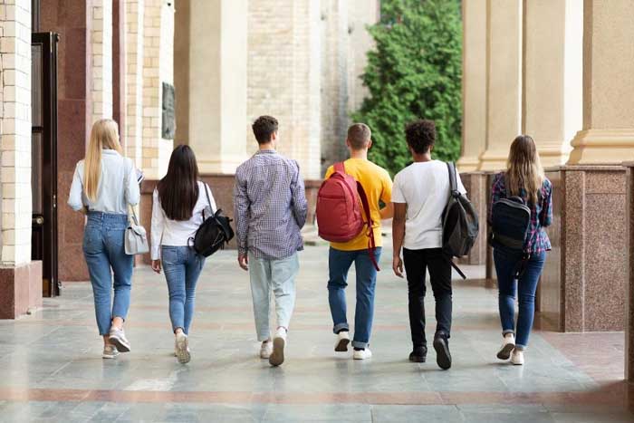 group of students with backpacks walking across campus