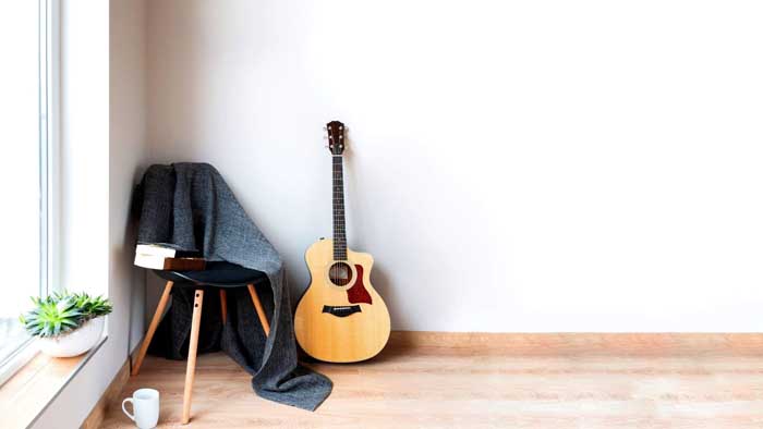 guitar leaning against a chair in a white room