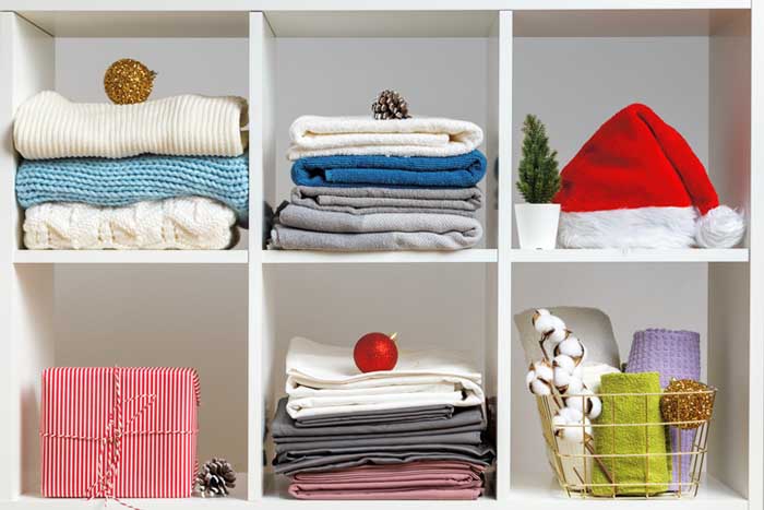 Bed linens, towels, sheets, knitted sweaters on the shelves decorated for the celebration of Christmas and New Year.