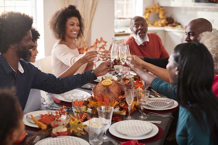 Multi generation mixed race family raise their glasses to make a toast at their Thanksgiving dinner table.