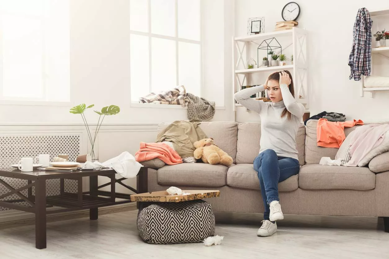 A woman sits on a couch grabbing her head looking stressed out