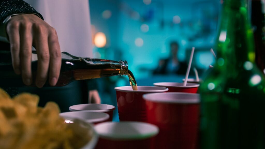 Close up of someone pouring a beer into a party cup