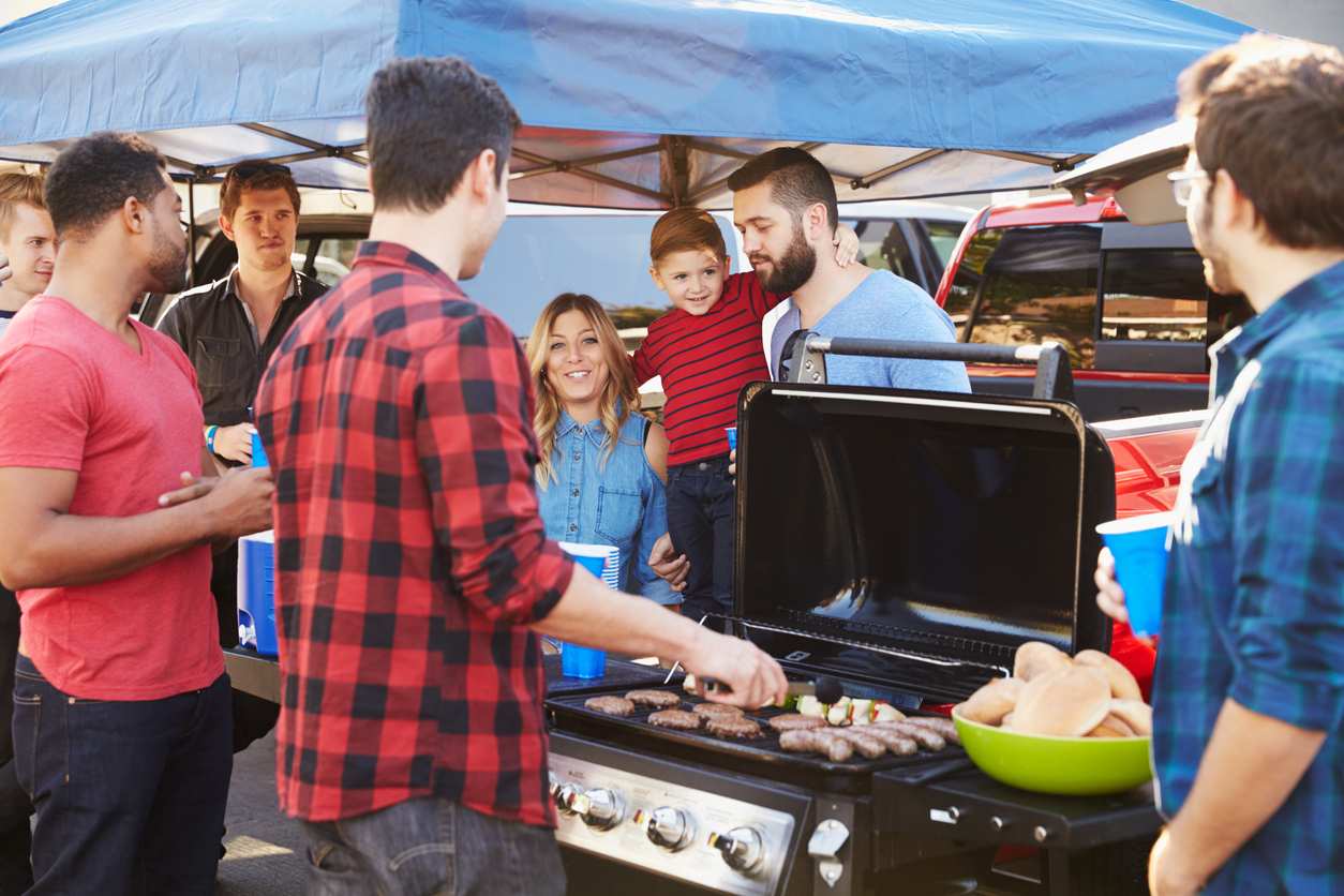 A group of friends gather around a grill to celebrate together