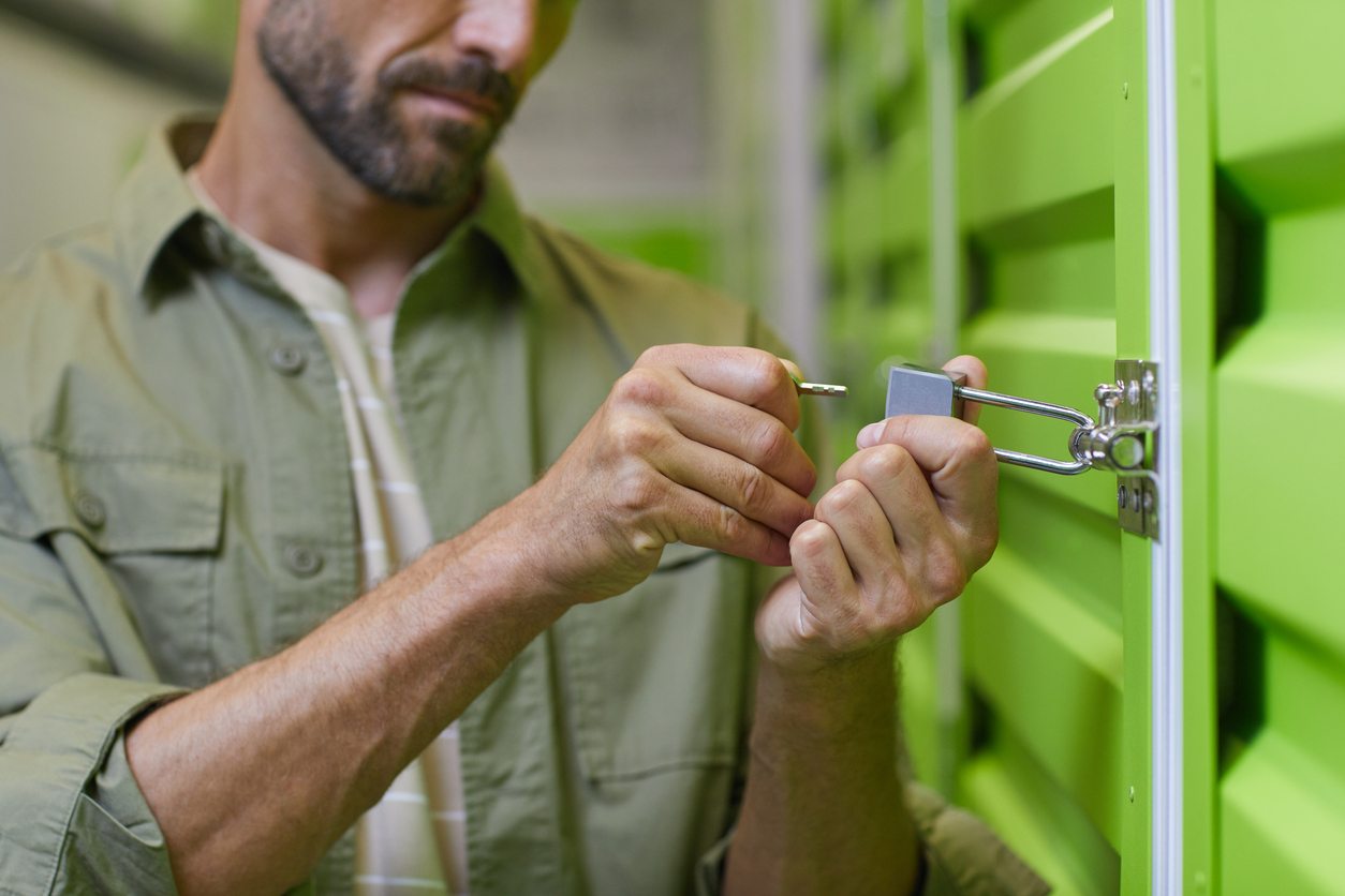 A man uses a key to unlock a storage unit with a bright green door
