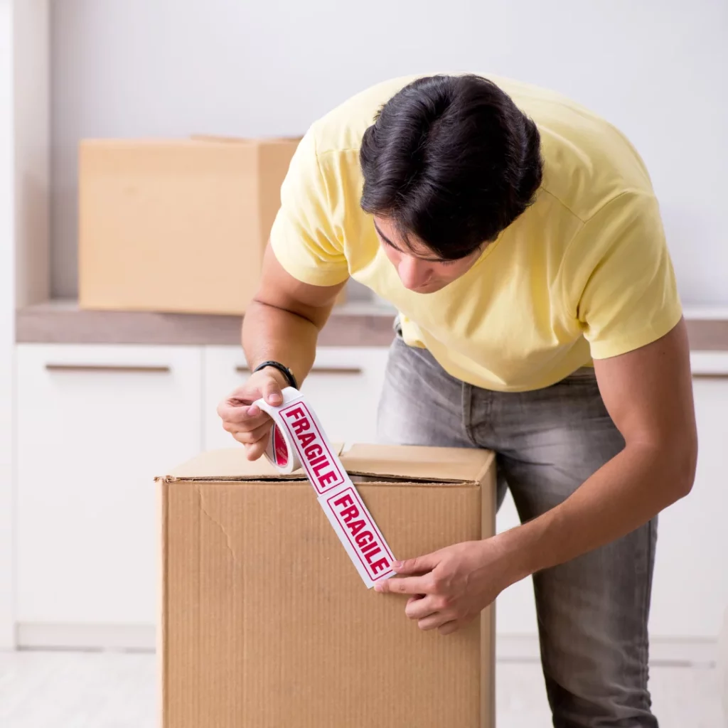 Man putting a fragile sticker on a moving box,