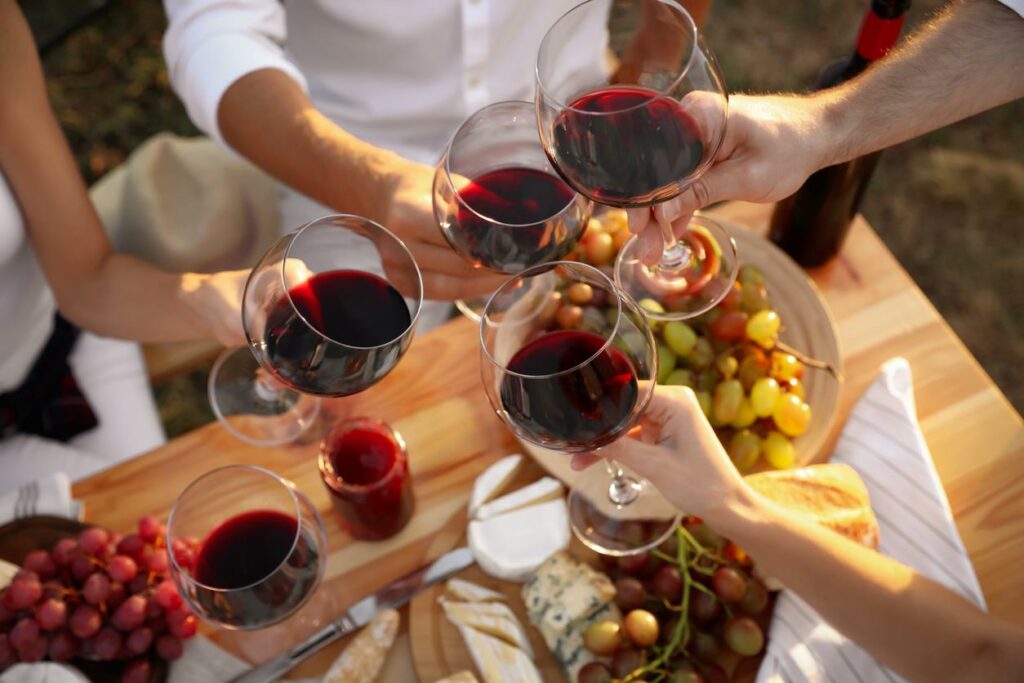 Friends holding glasses of wine at a table with food during sunset
