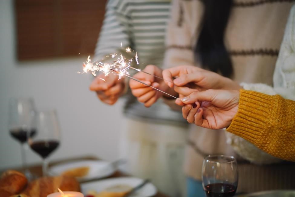 Group of friends celebrating new year’s with sparklers and food