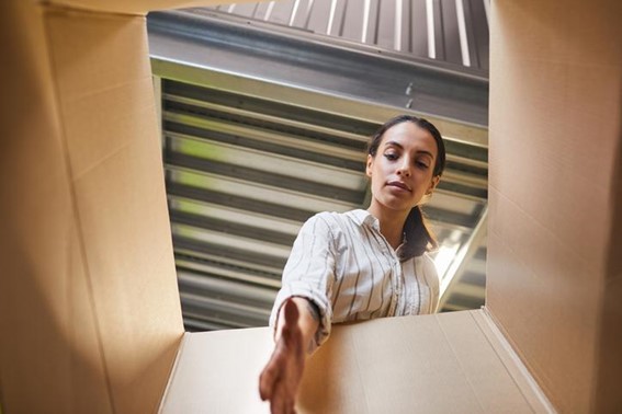 A woman reaches into a box of items in her downsizing self-storage unit.