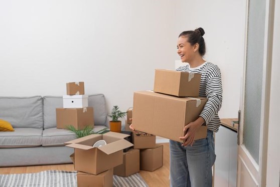 A woman holds boxes of things as she packs up and downsizes her home.