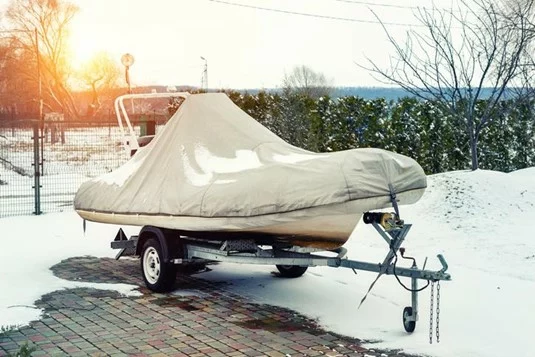 A boat parked outside in the winter with snow on the ground.