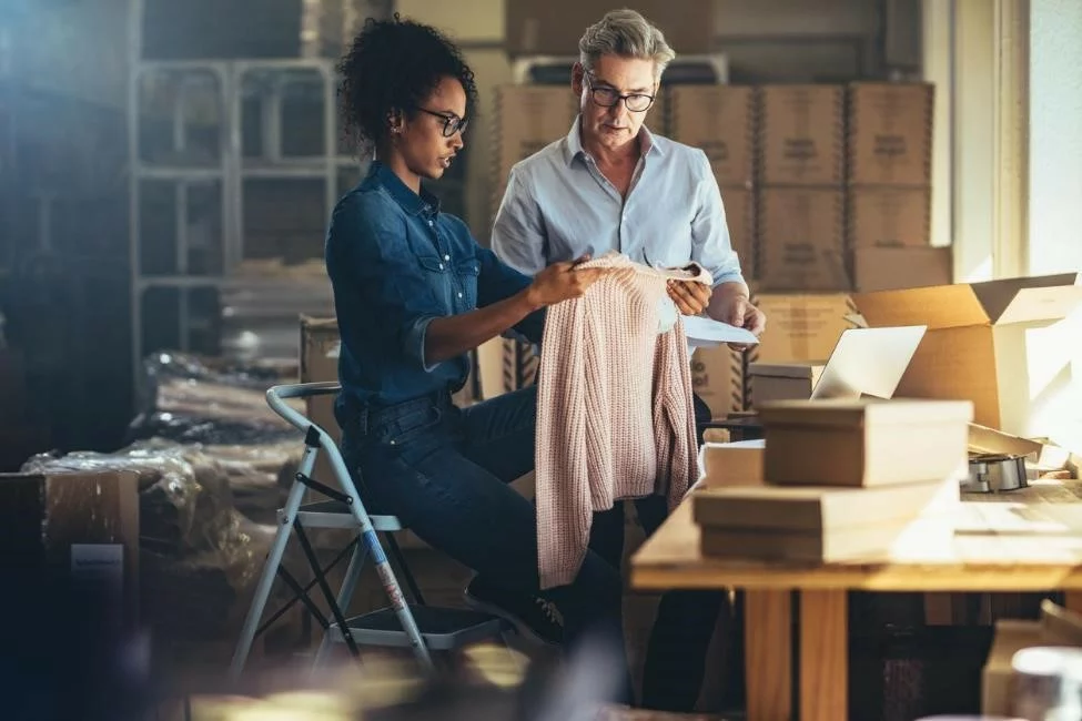 A pair of small business owners in a warehouse checking a product before shipping it.