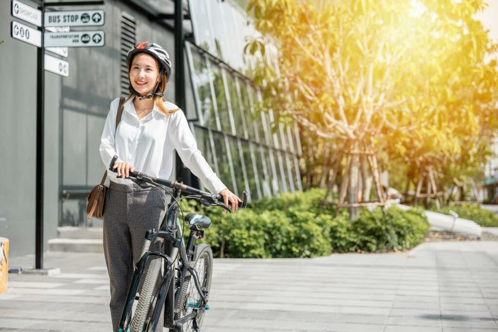 A businesswoman pushes her bicycle forward on the street.