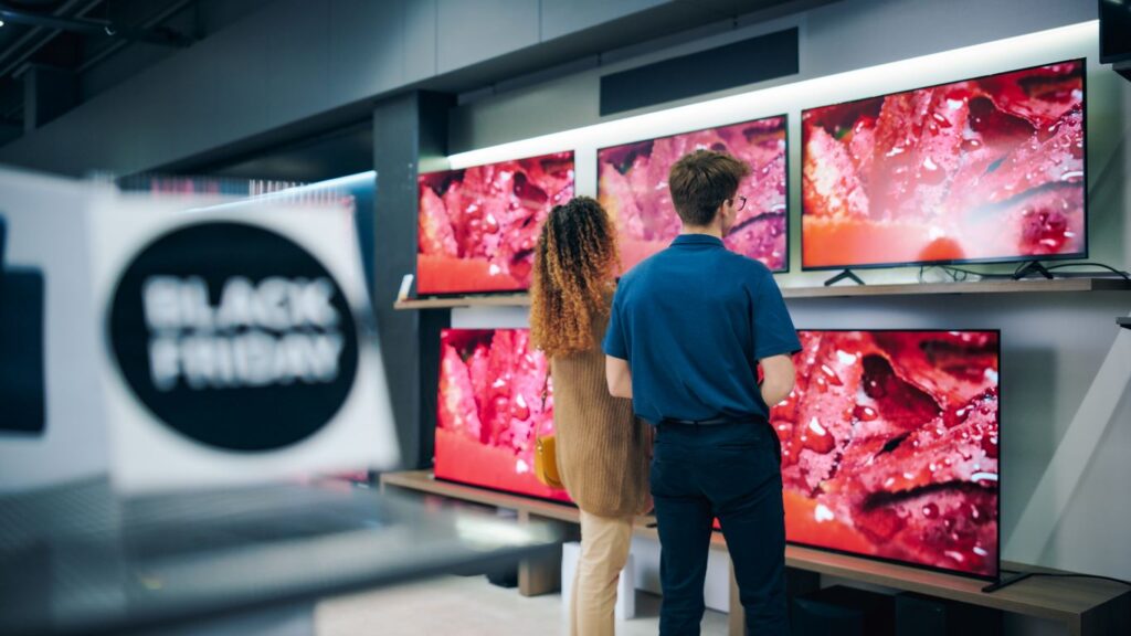 A couple looks at televisions together while Black Friday shopping.