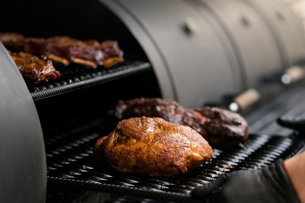 A barbecue pitboss puts meat on the smoker at his restaurant.