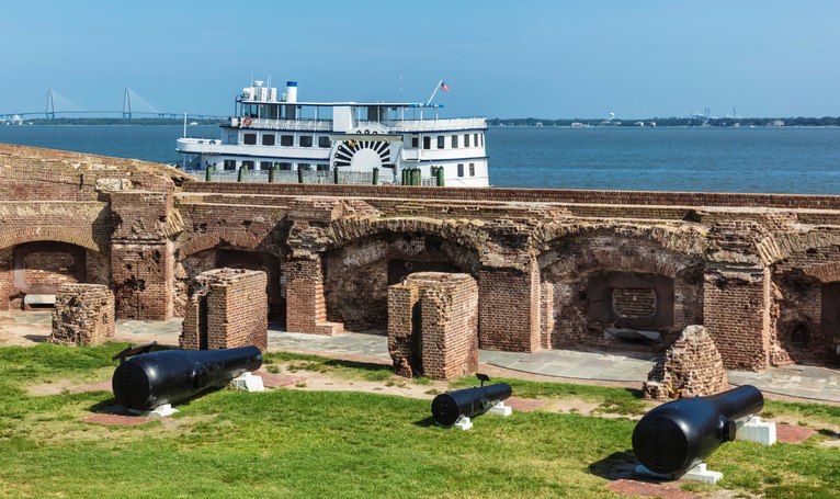 The historical grounds at Fort Sumter National Monument with a ferry on the water behind.