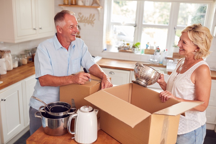 A senior couple laughs as they pack up their kitchen while downsizing.