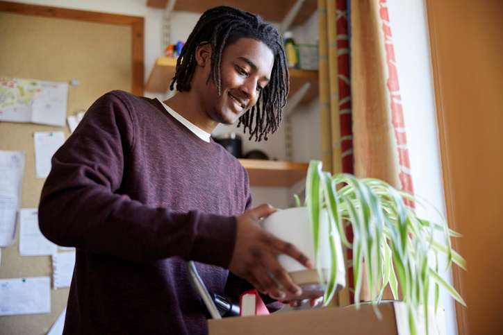 A college student smiles as he packs up his dorm room.