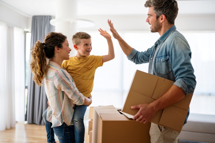 A man high-fives his son, who is held by his mother, as they move together.