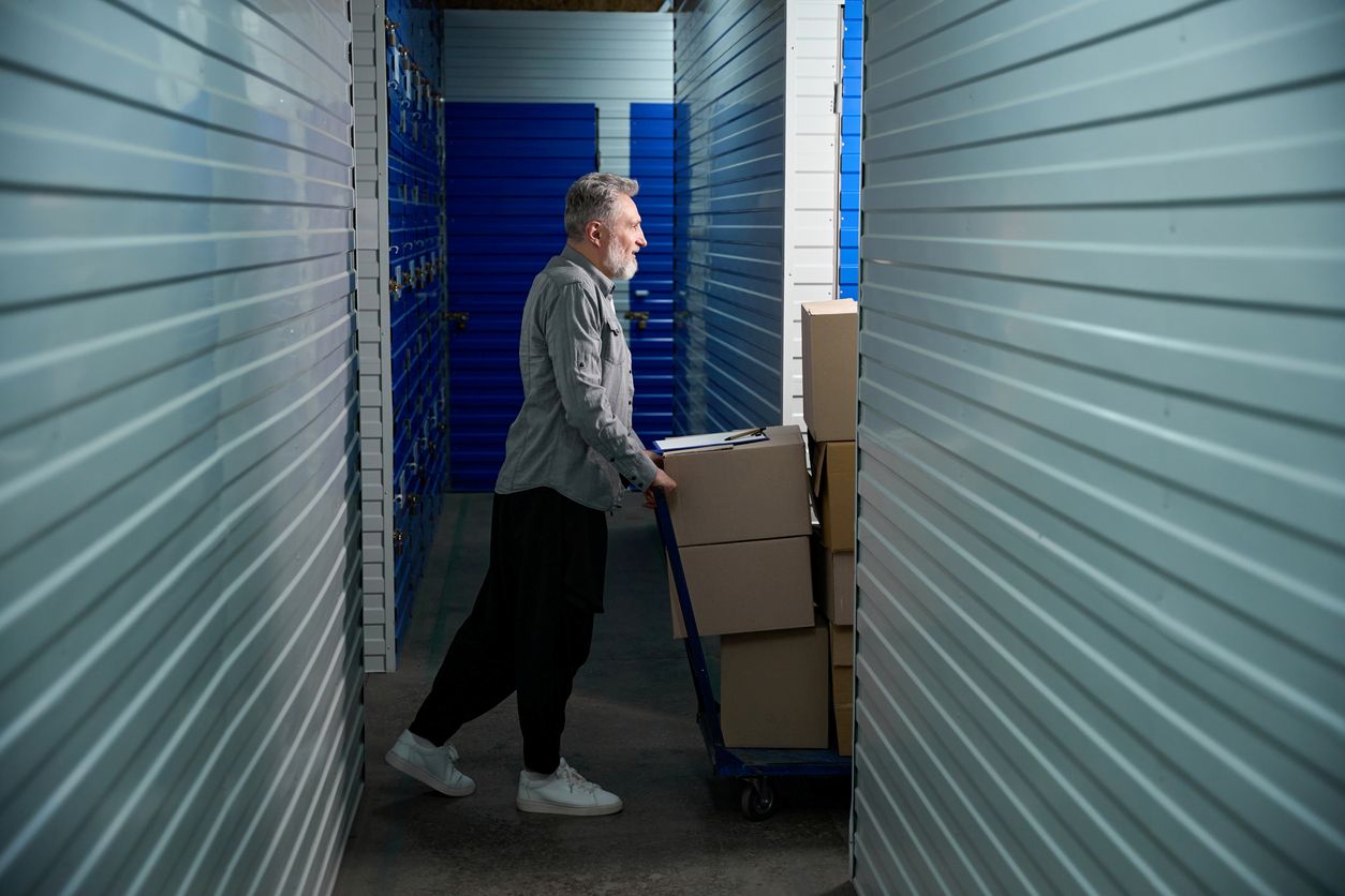 A man pushes a cart full of items into a self-storage unit.
