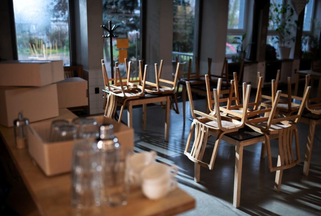 Chairs stacked on tables and boxes filled with items in a closed business.