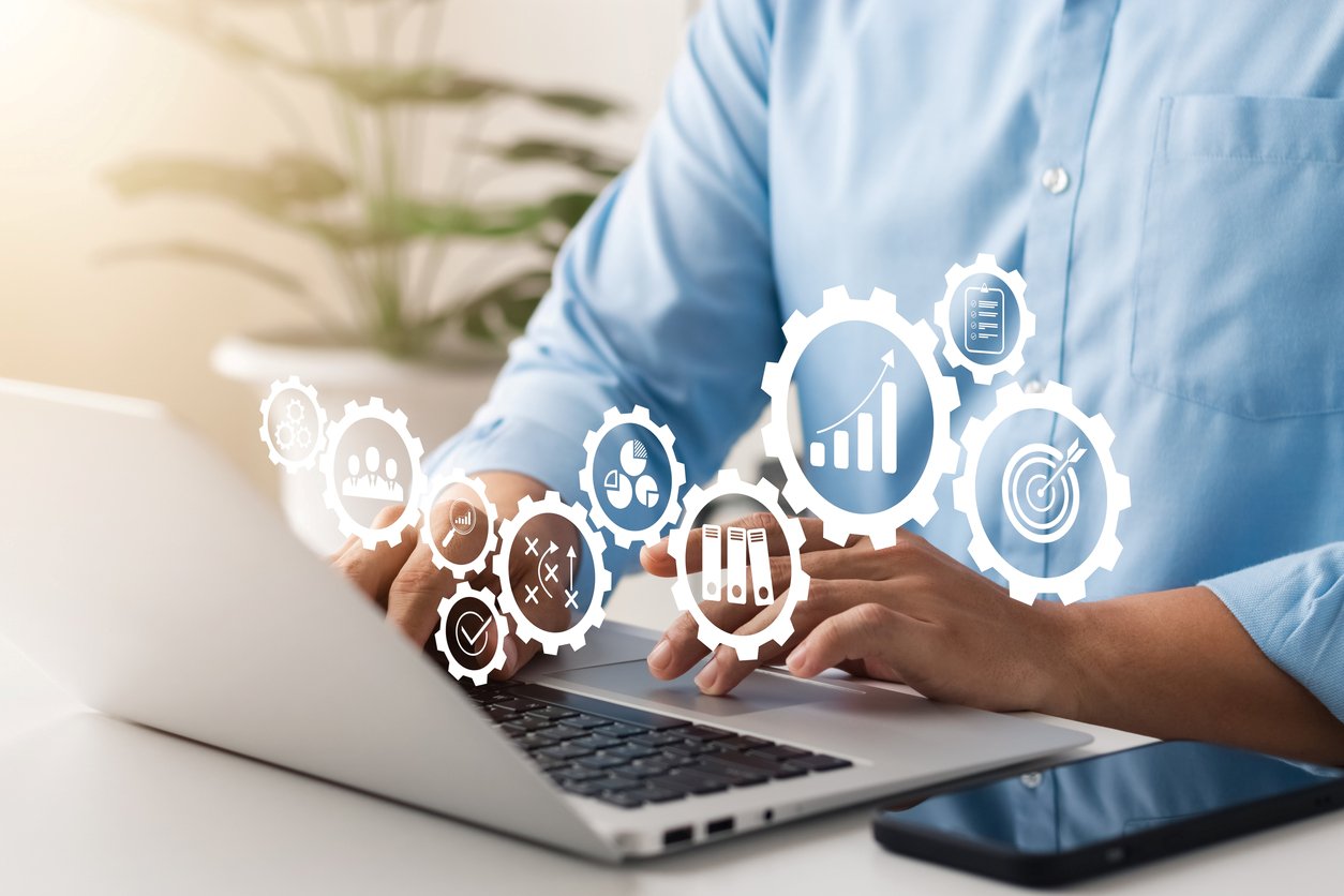 A man manages his automated self-storage system on his laptop, which is surrounded by tech-themed illustrations.