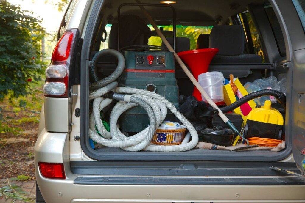 Trunk of a car full of cleaning supplies ready to go perform services on a house.
